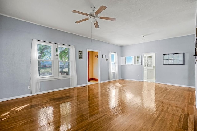 empty room featuring ceiling fan, wood-type flooring, and a wealth of natural light