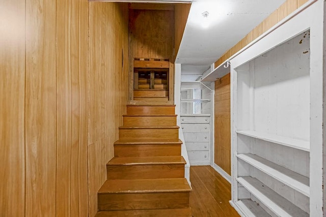 stairway with hardwood / wood-style flooring and wood walls