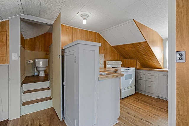 kitchen featuring white cabinetry, white electric range oven, vaulted ceiling, wood walls, and light hardwood / wood-style floors