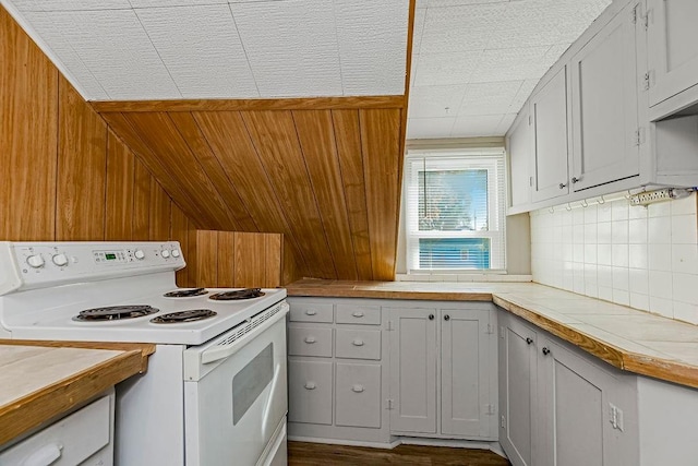 kitchen featuring white range with electric stovetop, white cabinets, wooden walls, and dark hardwood / wood-style floors