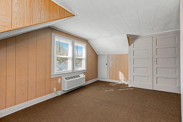 additional living space featuring lofted ceiling, wooden walls, and dark carpet