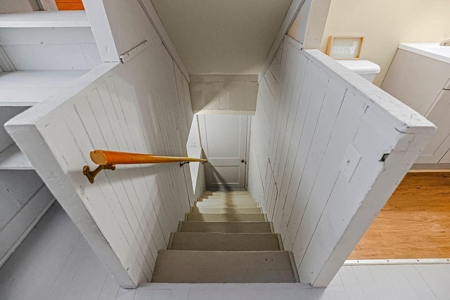 stairs featuring hardwood / wood-style floors and wood walls