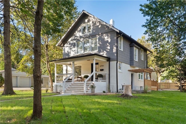 view of front of house featuring a porch, a front yard, an outbuilding, and a garage