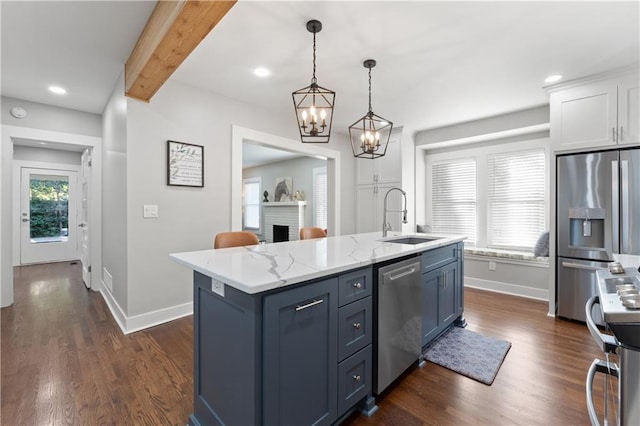 kitchen with appliances with stainless steel finishes, sink, an island with sink, beamed ceiling, and pendant lighting