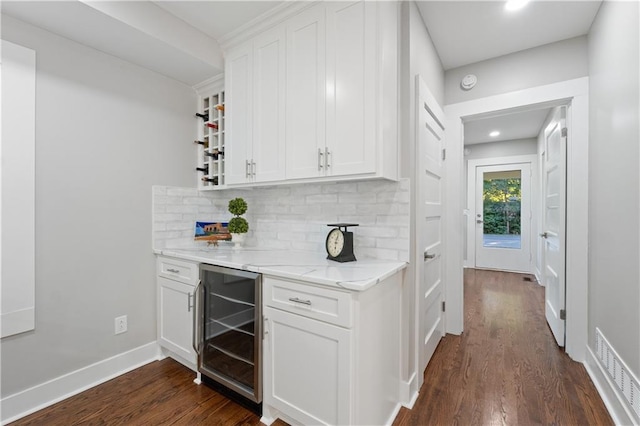 bar featuring dark wood-type flooring, white cabinetry, light stone countertops, and beverage cooler