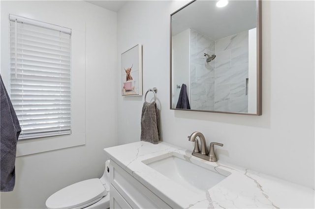 bathroom with vanity, tiled shower, and toilet