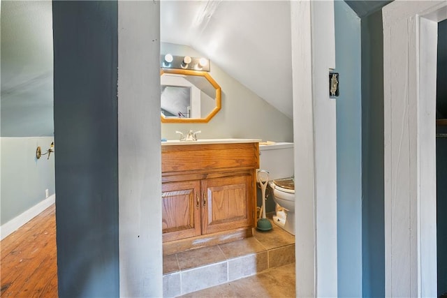 bathroom with toilet, lofted ceiling, hardwood / wood-style floors, and vanity