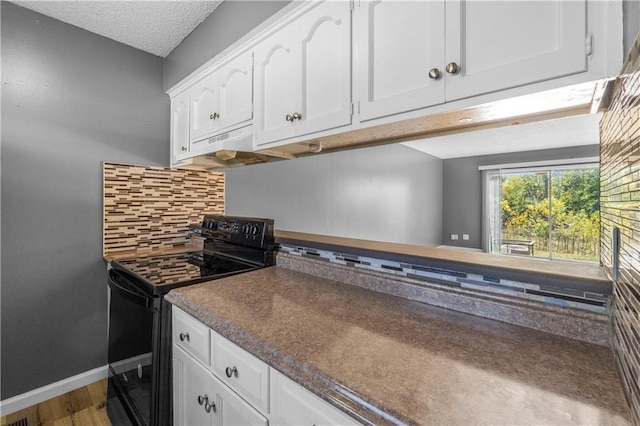 kitchen featuring tasteful backsplash, black range with electric stovetop, white cabinets, and extractor fan