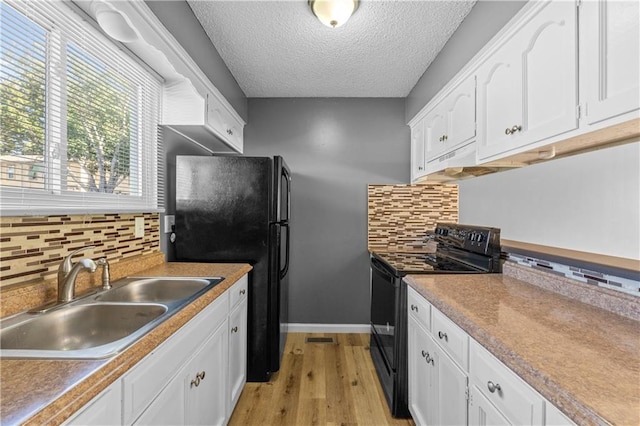 kitchen featuring black appliances, white cabinetry, and sink