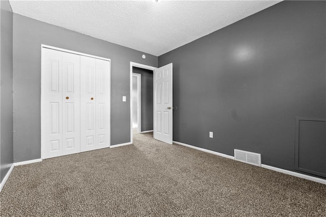 unfurnished bedroom with carpet flooring, a textured ceiling, and a closet