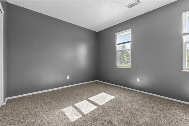 carpeted empty room with a textured ceiling