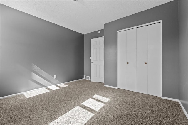 unfurnished bedroom with carpet floors, a textured ceiling, and a closet