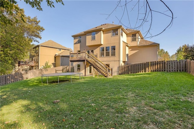 back of property featuring a yard and a trampoline