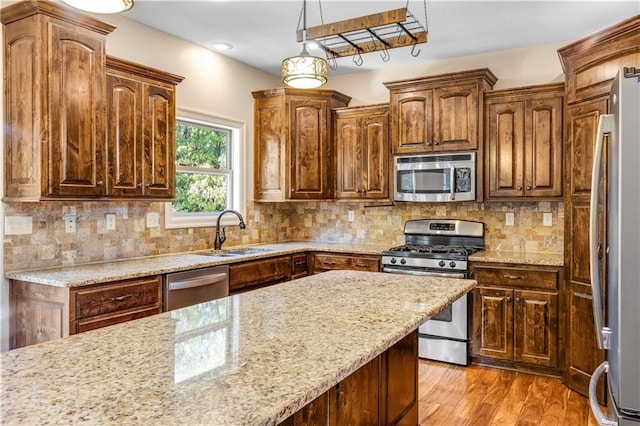 kitchen featuring pendant lighting, decorative backsplash, stainless steel appliances, and light wood-type flooring