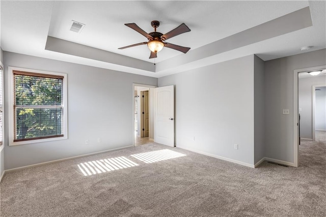 spare room featuring ceiling fan, a raised ceiling, and light colored carpet