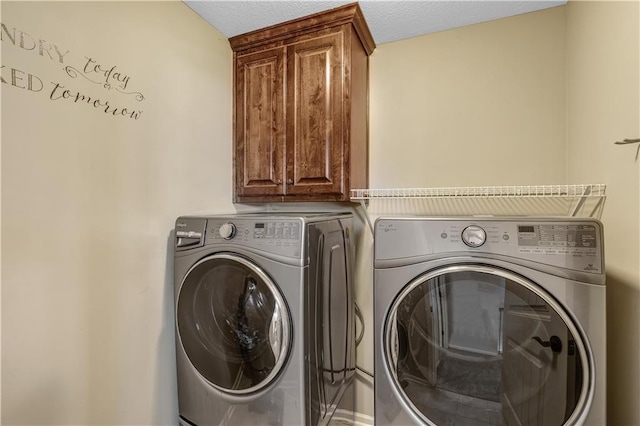 washroom with washer and clothes dryer, a textured ceiling, and cabinets