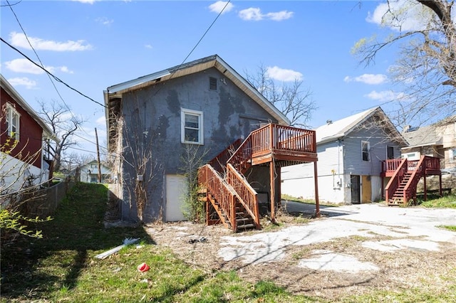 rear view of house featuring a wooden deck and a garage