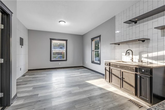 interior space with light hardwood / wood-style flooring, dark stone countertops, dark brown cabinetry, and sink