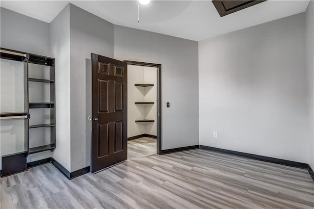 unfurnished bedroom featuring a spacious closet, light hardwood / wood-style flooring, and a closet