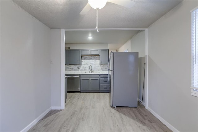 kitchen featuring gray cabinets, appliances with stainless steel finishes, sink, backsplash, and a textured ceiling