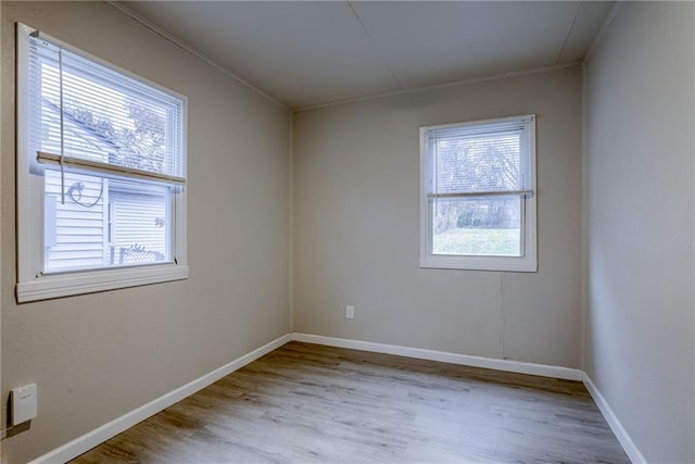 empty room with ornamental molding and light hardwood / wood-style flooring