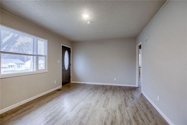 entryway with crown molding, a textured ceiling, and light wood-type flooring