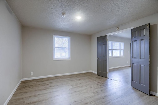 unfurnished room featuring light hardwood / wood-style floors and a textured ceiling