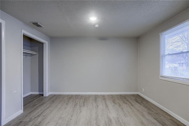 unfurnished bedroom featuring light hardwood / wood-style flooring, a closet, and a textured ceiling