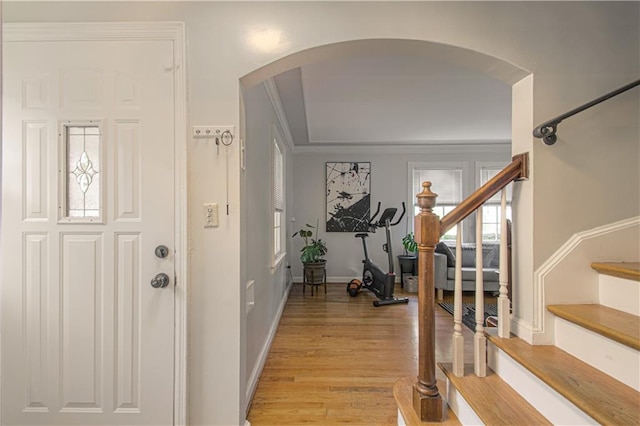 entrance foyer featuring light wood-type flooring, a healthy amount of sunlight, and crown molding