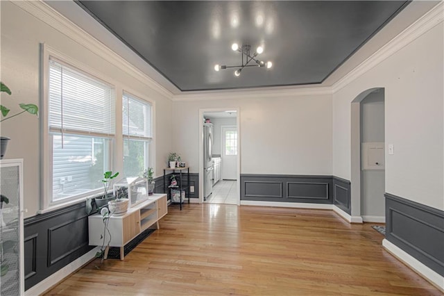 interior space featuring light hardwood / wood-style floors, crown molding, an inviting chandelier, and a healthy amount of sunlight