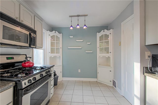 kitchen featuring white cabinets, track lighting, hanging light fixtures, appliances with stainless steel finishes, and light tile patterned floors