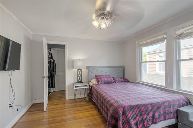 bedroom featuring ceiling fan, light hardwood / wood-style flooring, crown molding, and a closet