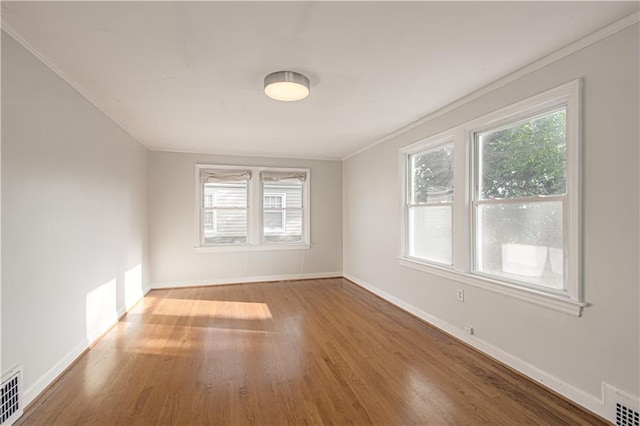 spare room featuring ornamental molding, a healthy amount of sunlight, and hardwood / wood-style floors