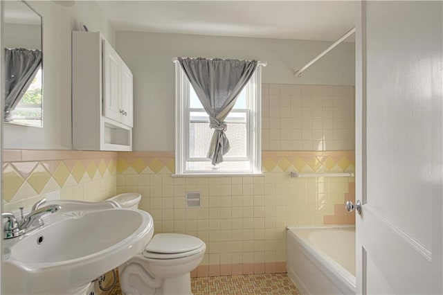 bathroom with toilet, a tub to relax in, tile patterned flooring, and tile walls