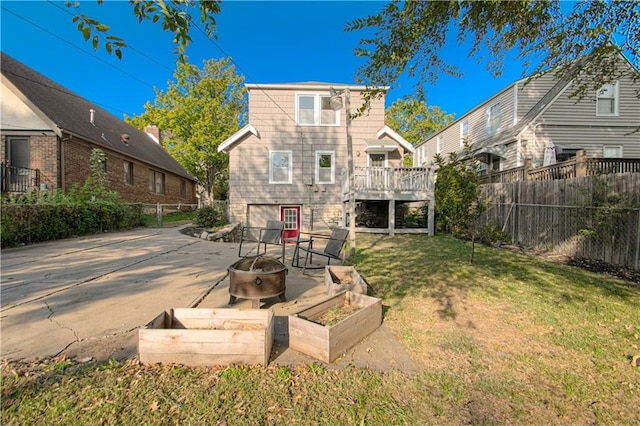 back of property featuring a wooden deck, a lawn, a patio area, and an outdoor fire pit