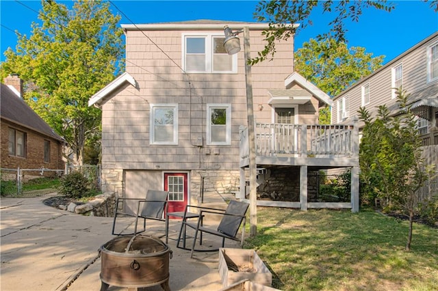 rear view of house with a yard, a wooden deck, a patio, and a fire pit