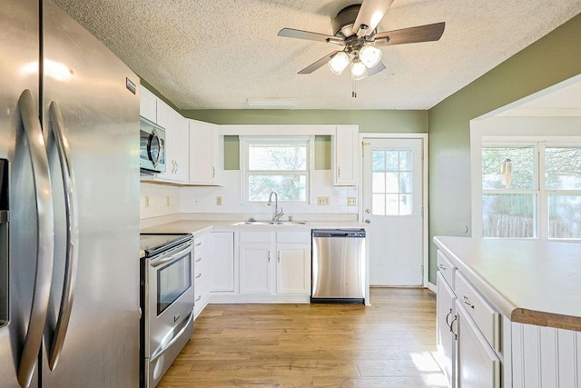 kitchen with white cabinets, sink, light hardwood / wood-style floors, and stainless steel appliances