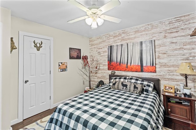 bedroom with wooden walls, dark hardwood / wood-style flooring, and ceiling fan