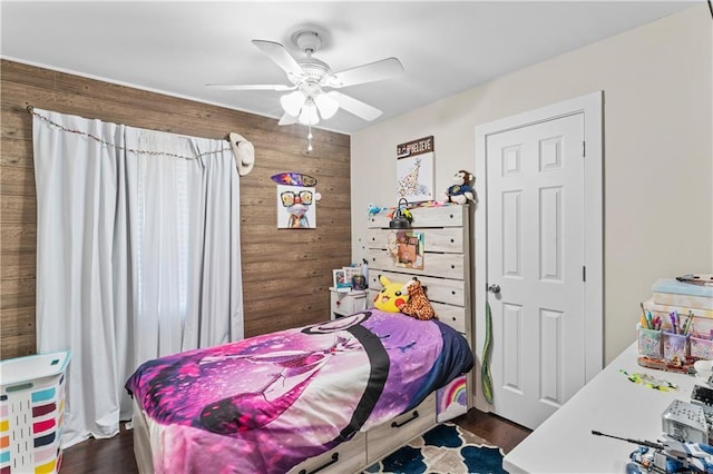 bedroom featuring dark hardwood / wood-style floors, ceiling fan, and wood walls