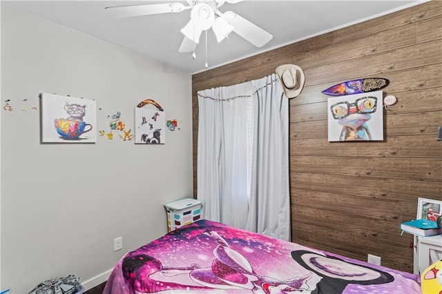 bedroom featuring ceiling fan and wood walls