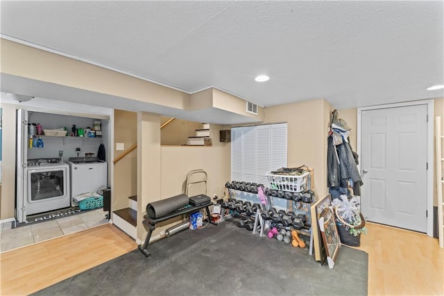 exercise area featuring light hardwood / wood-style floors, washing machine and dryer, and a textured ceiling