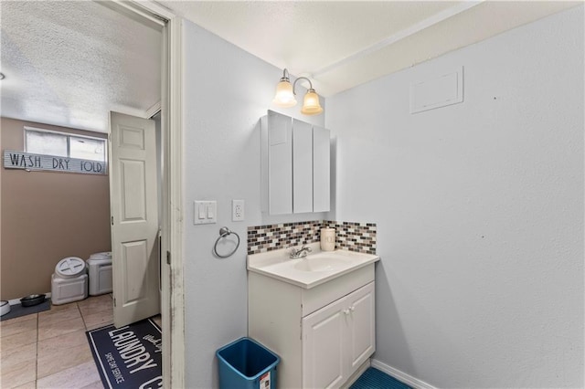 bathroom featuring tile patterned floors, decorative backsplash, vanity, and a textured ceiling