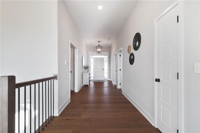 hallway with dark hardwood / wood-style floors and an inviting chandelier