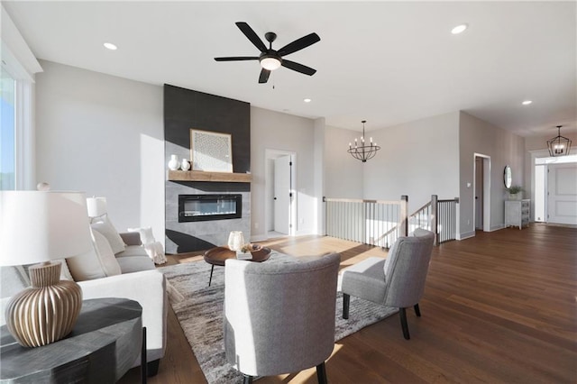 living room featuring a fireplace, ceiling fan with notable chandelier, and dark hardwood / wood-style flooring