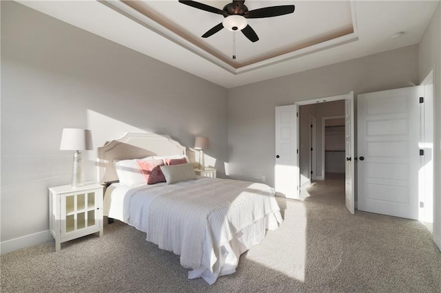 carpeted bedroom with ceiling fan and a raised ceiling