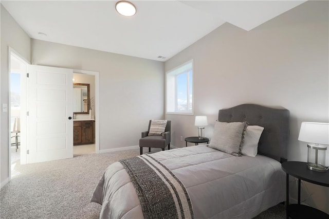 bedroom with ensuite bathroom and carpet flooring