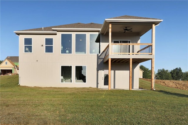 rear view of house with ceiling fan and a yard