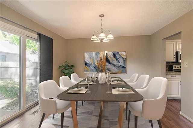 dining space featuring dark wood-type flooring, a chandelier, and a textured ceiling