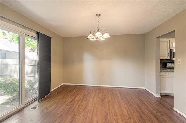 spare room with a textured ceiling, dark hardwood / wood-style flooring, and a notable chandelier