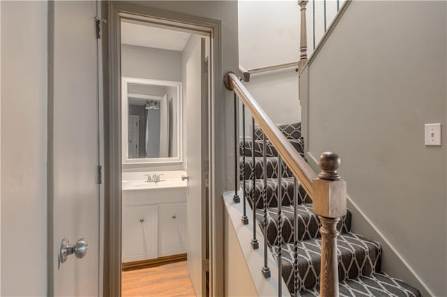 staircase with wood-type flooring and sink